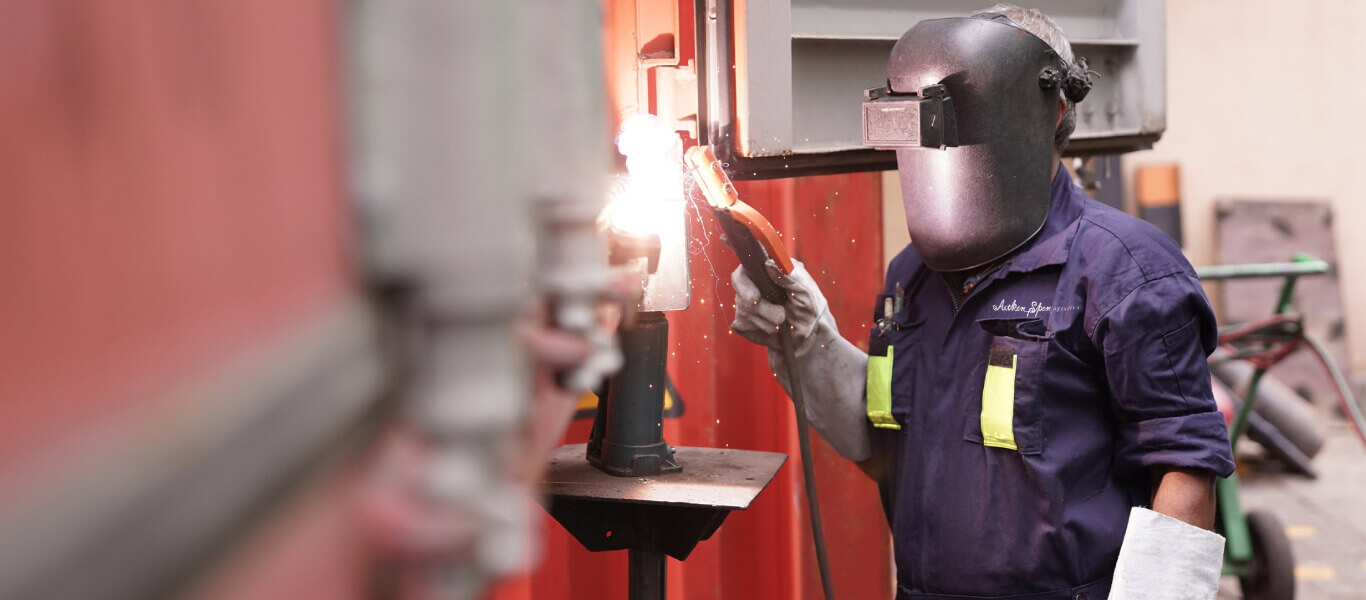 A skilled worker repairing and rigging shipping containers.