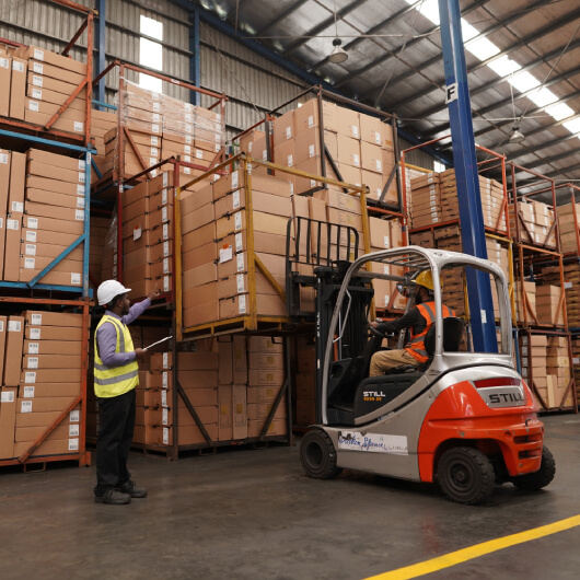 An instructor controlling a forklift in the warehouse