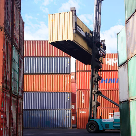 A container stacker crane lifting up stacking container boxes in yard